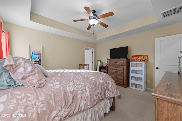 carpeted bedroom featuring ceiling fan and a raised ceiling