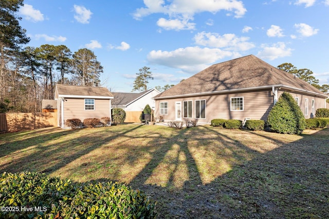 rear view of house with a storage unit and a yard