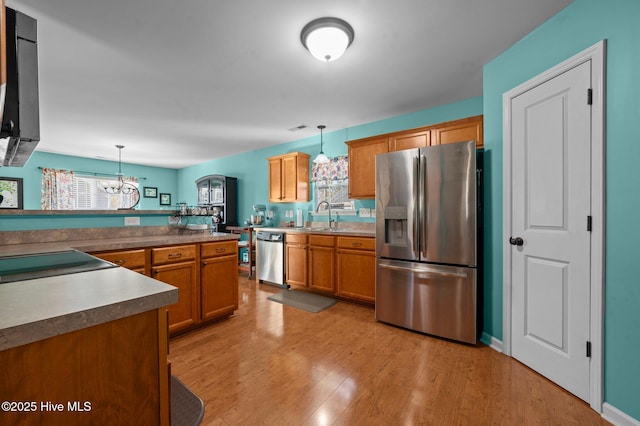 kitchen with sink, hanging light fixtures, light hardwood / wood-style flooring, a notable chandelier, and stainless steel appliances