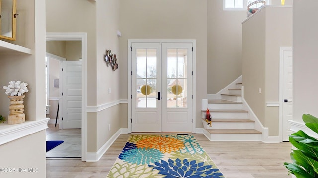 foyer entrance featuring a towering ceiling, light hardwood / wood-style floors, and french doors