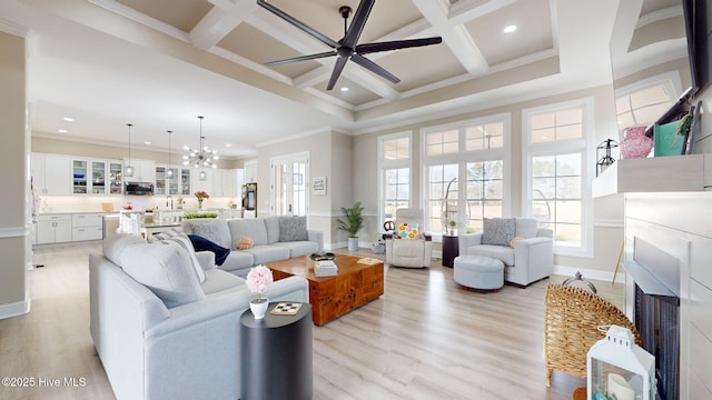 living room with coffered ceiling, ornamental molding, light hardwood / wood-style floors, beamed ceiling, and ceiling fan with notable chandelier