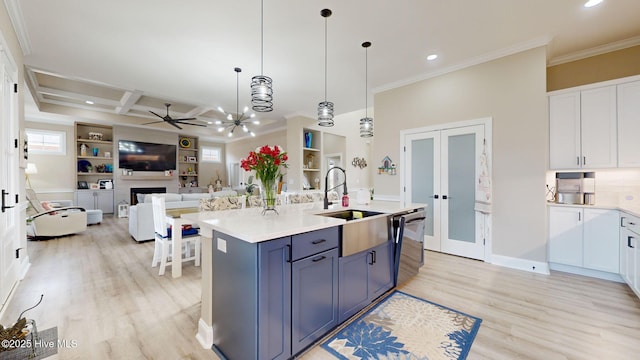 kitchen featuring pendant lighting, sink, a kitchen island with sink, white cabinets, and french doors