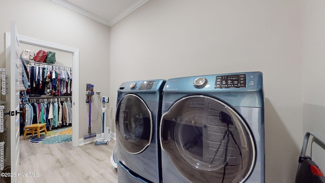 clothes washing area with crown molding, light hardwood / wood-style floors, and washing machine and clothes dryer