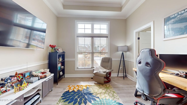 home office featuring ornamental molding, a tray ceiling, and light hardwood / wood-style flooring