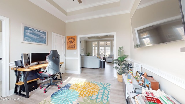 home office featuring ceiling fan, ornamental molding, a tray ceiling, and light hardwood / wood-style floors