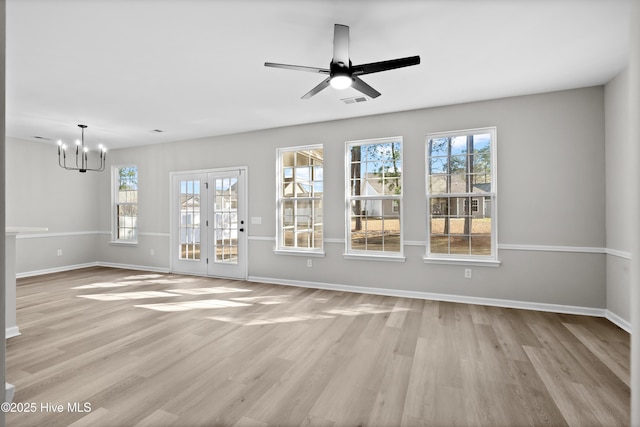 unfurnished living room featuring ceiling fan with notable chandelier and light hardwood / wood-style flooring