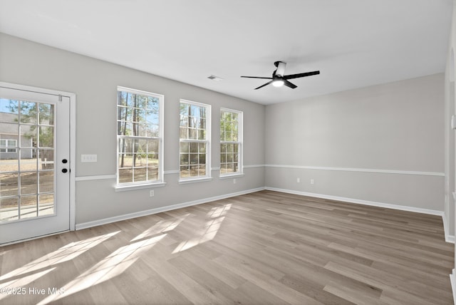 empty room with ceiling fan, hardwood / wood-style floors, and a healthy amount of sunlight