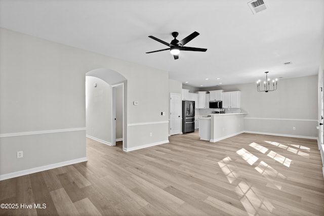 unfurnished living room featuring ceiling fan with notable chandelier and light wood-type flooring