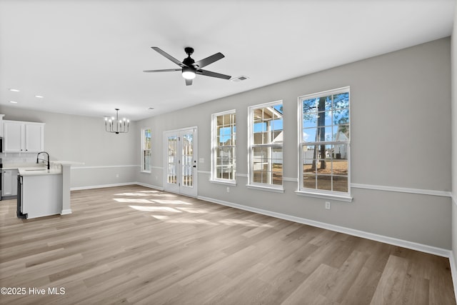 unfurnished living room with sink, light hardwood / wood-style floors, and ceiling fan with notable chandelier