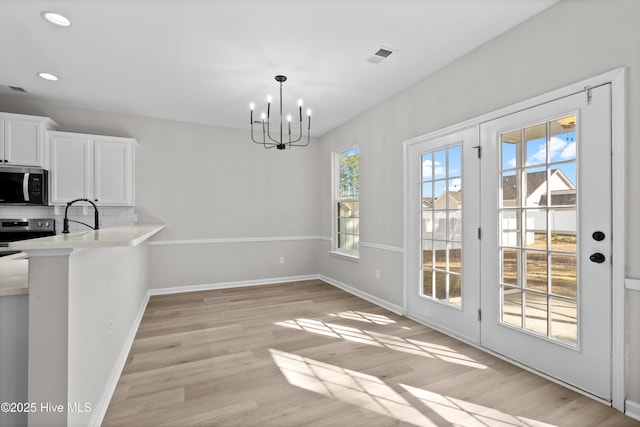 unfurnished dining area with light hardwood / wood-style flooring, sink, and a chandelier