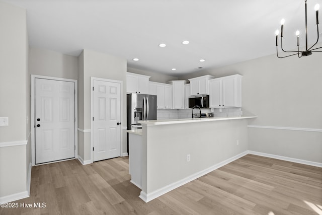 kitchen with light hardwood / wood-style flooring, white cabinetry, stainless steel appliances, kitchen peninsula, and tasteful backsplash