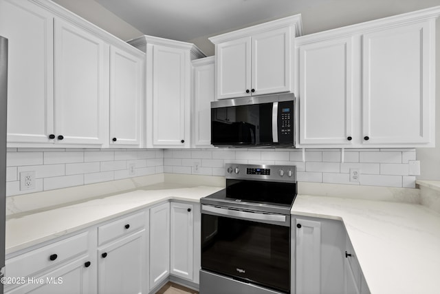 kitchen featuring white cabinetry, backsplash, stainless steel appliances, and light stone counters