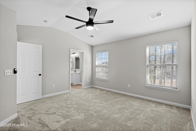 unfurnished bedroom featuring ceiling fan, lofted ceiling, ensuite bath, and light colored carpet