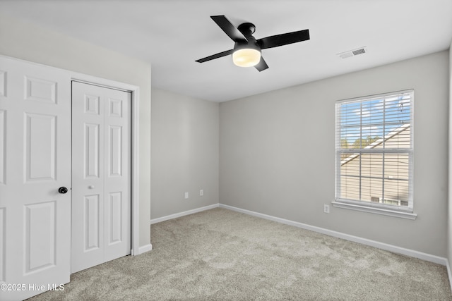 unfurnished bedroom featuring light carpet, a closet, and ceiling fan