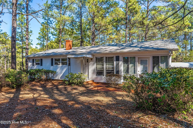 view of front of home featuring a chimney and a sunroom