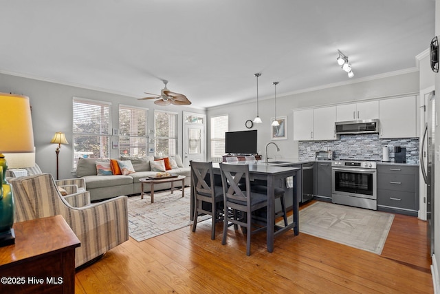 kitchen with decorative light fixtures, white cabinetry, sink, kitchen peninsula, and stainless steel appliances