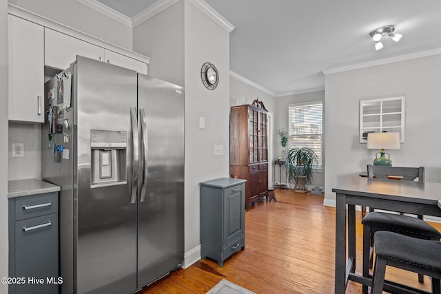 kitchen featuring light hardwood / wood-style flooring, crown molding, stainless steel fridge, and gray cabinets