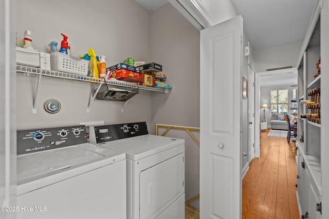 clothes washing area featuring separate washer and dryer and light wood-type flooring