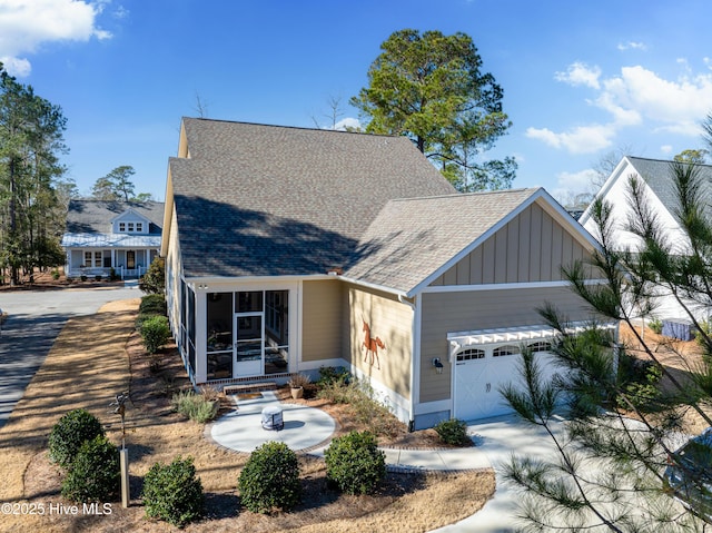 3604 Haughton Ln, Castle Hayne, NC 28429 - view of front facade with board and batten siding, an attached garage, roof with shingles, a sunroom, and driveway