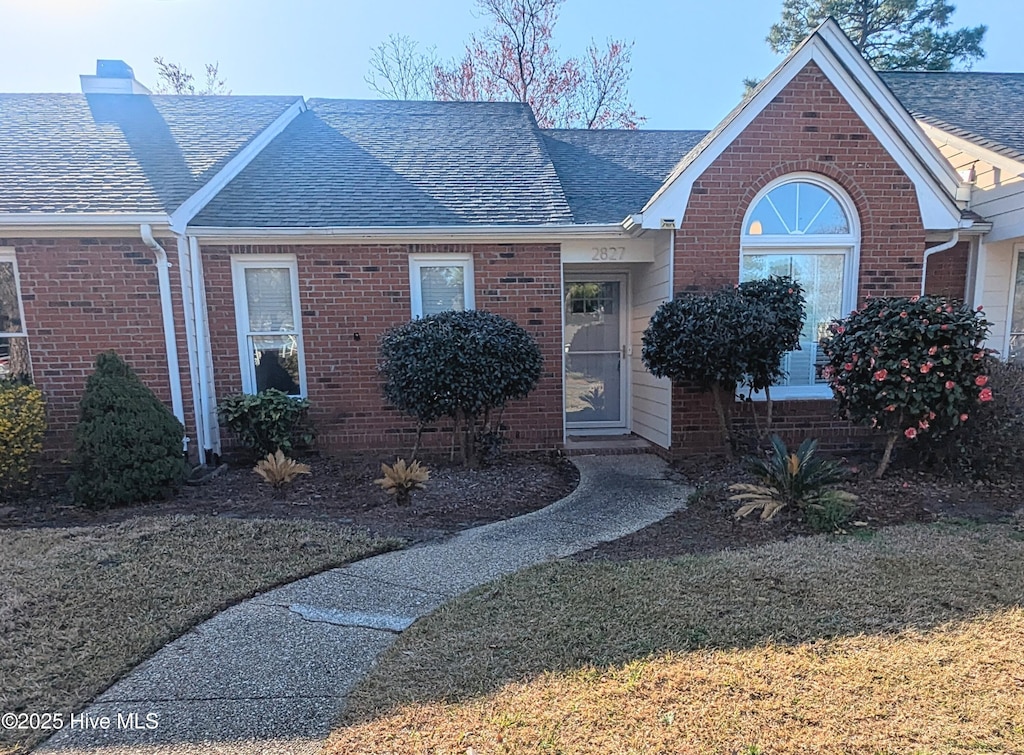 view of front of house featuring brick siding and a shingled roof