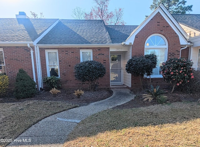 view of front of house featuring brick siding and a shingled roof