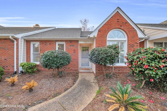 view of front of house featuring brick siding and roof with shingles