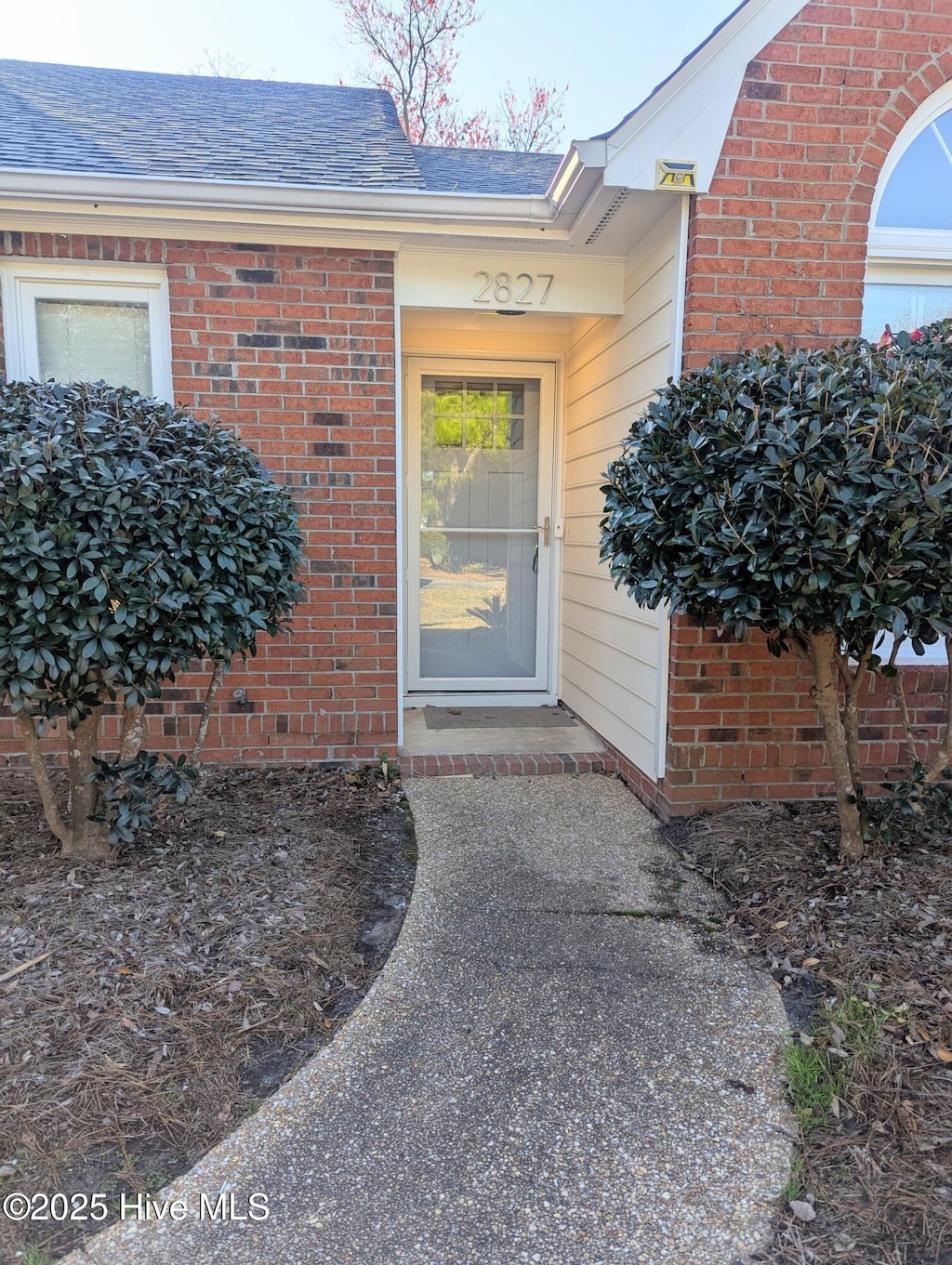 property entrance featuring brick siding and roof with shingles