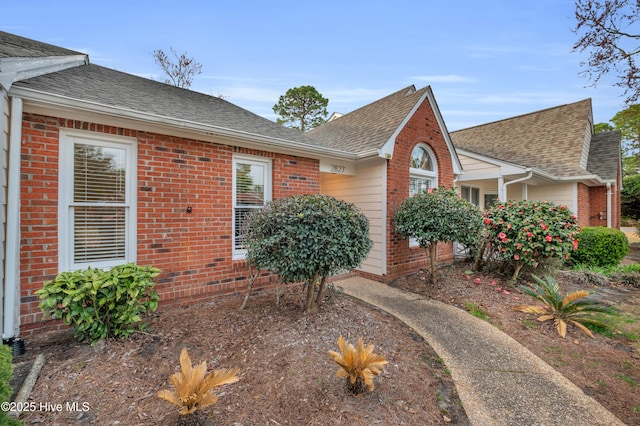 view of front of house with brick siding and a shingled roof