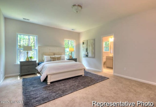 bedroom featuring light colored carpet and ensuite bathroom