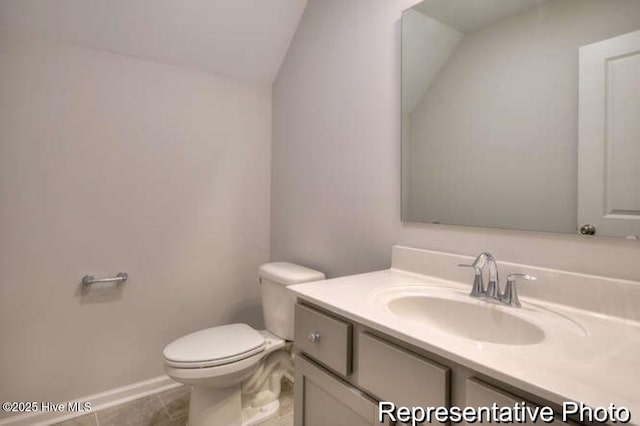 bathroom with vanity, tile patterned flooring, vaulted ceiling, and toilet