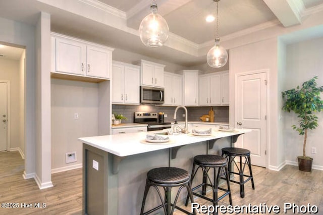 kitchen featuring stainless steel appliances, a center island with sink, white cabinets, and light hardwood / wood-style flooring