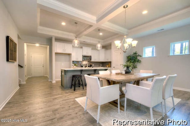 dining area featuring coffered ceiling, crown molding, a chandelier, light hardwood / wood-style flooring, and beamed ceiling