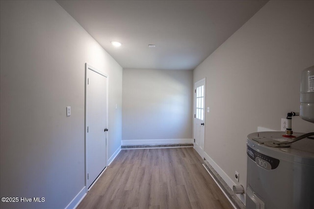 corridor with light hardwood / wood-style floors and water heater