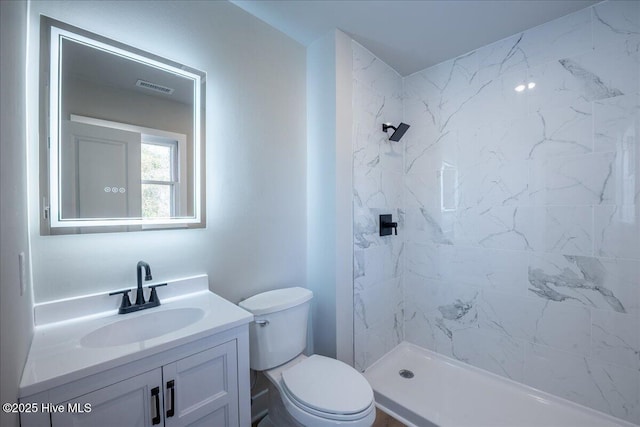 bathroom with vanity, toilet, and tiled shower