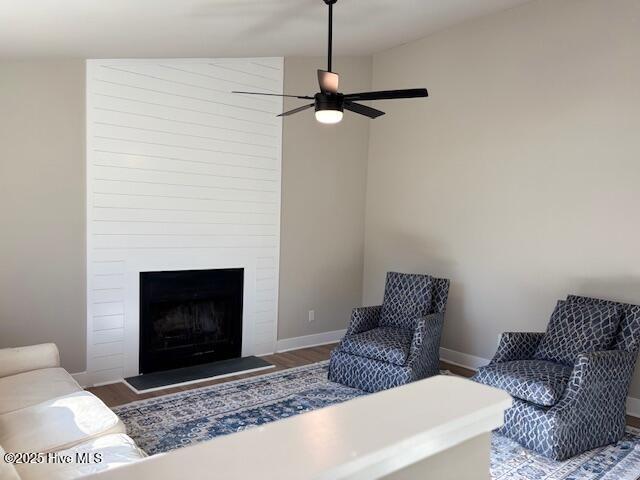 living room featuring ceiling fan, wood-type flooring, and a fireplace