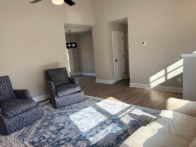 living area with ceiling fan with notable chandelier and hardwood / wood-style floors