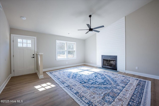 unfurnished living room featuring ceiling fan, a large fireplace, vaulted ceiling, and light wood-type flooring