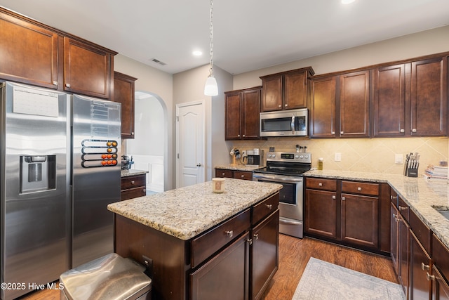 kitchen featuring hanging light fixtures, backsplash, stainless steel appliances, and dark hardwood / wood-style floors