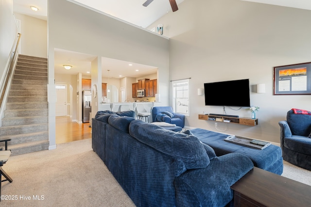 living room featuring light carpet, high vaulted ceiling, and ceiling fan