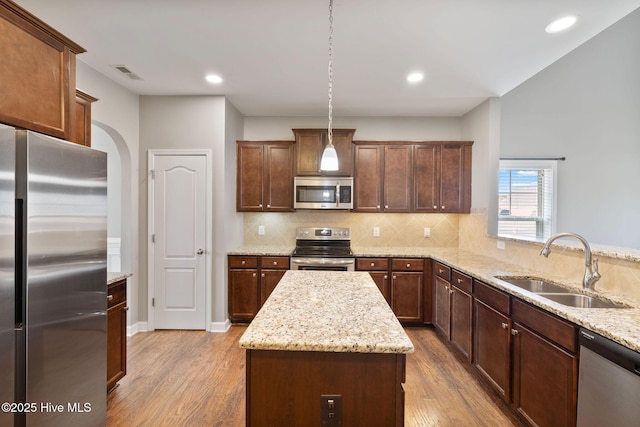 kitchen with tasteful backsplash, visible vents, a sink, wood finished floors, and stainless steel appliances