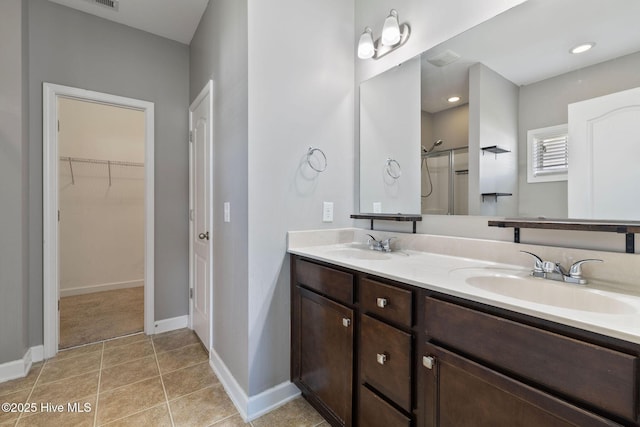 bathroom featuring walk in shower, double vanity, a sink, and a walk in closet