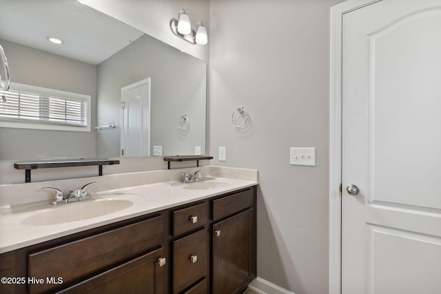 bathroom with a sink, baseboards, and double vanity