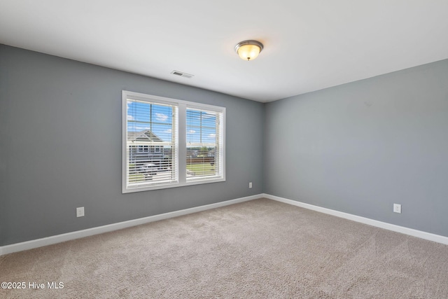 carpeted spare room with visible vents and baseboards