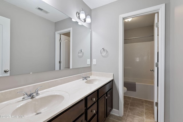 bathroom with toilet, double vanity, a sink, and visible vents