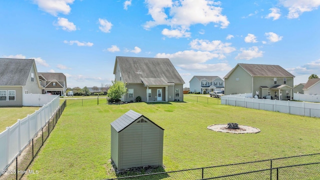 view of yard featuring a residential view, a fire pit, and a fenced backyard