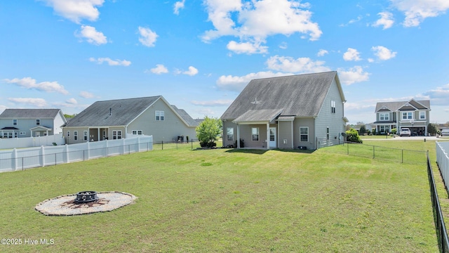 rear view of property with an outdoor fire pit, a fenced backyard, and a lawn