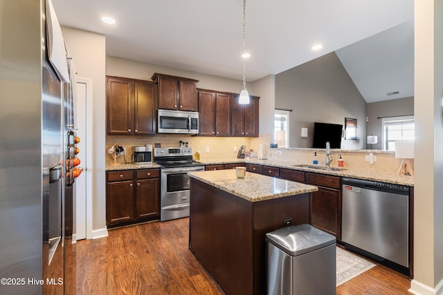 kitchen with sink, light stone countertops, a center island, and appliances with stainless steel finishes