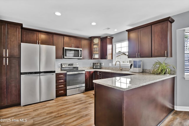 kitchen featuring sink, dark brown cabinets, stainless steel appliances, kitchen peninsula, and light wood-type flooring