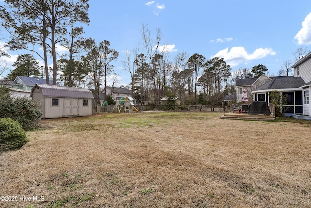 view of yard featuring a playground, a sunroom, and a storage shed