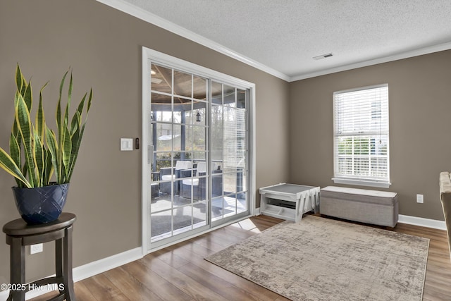 doorway featuring hardwood / wood-style flooring, ornamental molding, and a textured ceiling